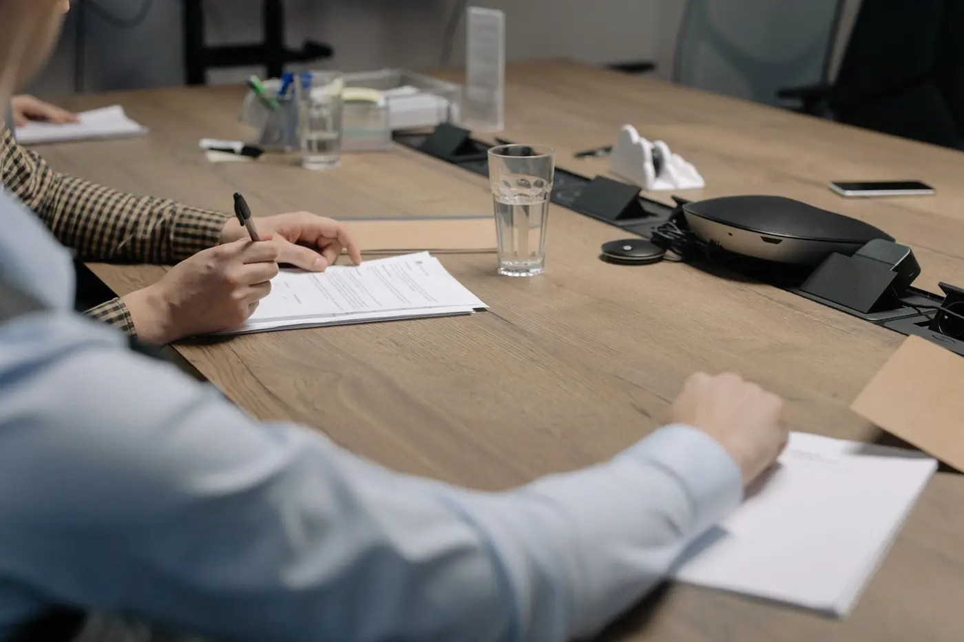 Printed documents being signed across a meeting table